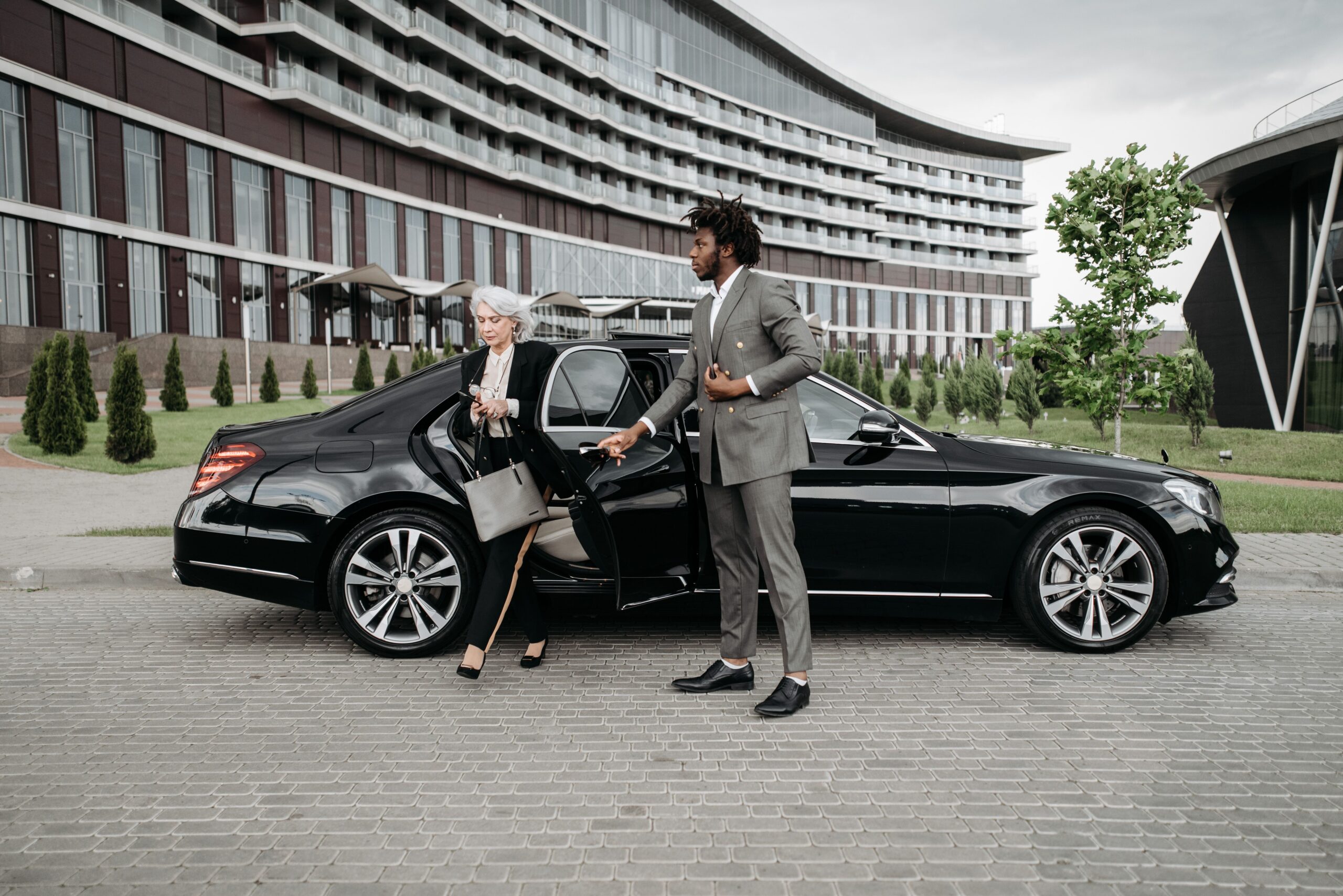 Professional chauffeur beside a premium vehicle
